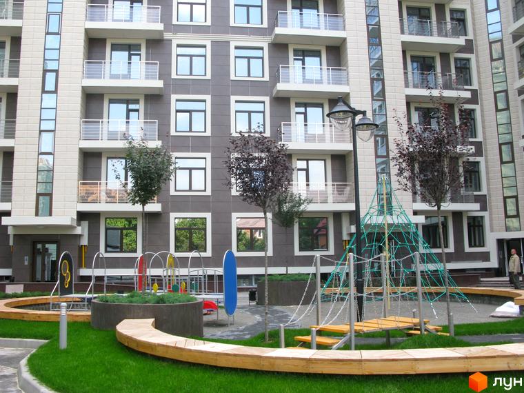Зовнішній вигляд житлового комплексу ЖК Zverinetskiy з дитячим майданчиком та зеленими насадженнями на прибудинковій території.