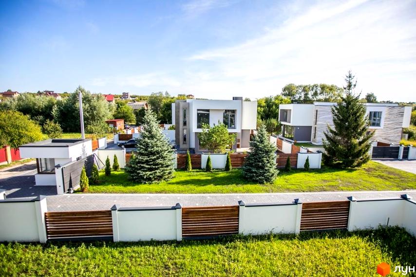 Котеджне містечко Riviera Gold: двоповерхові будинки з великими вікнами та зеленою прибудинковою територією, огородженою парканом.