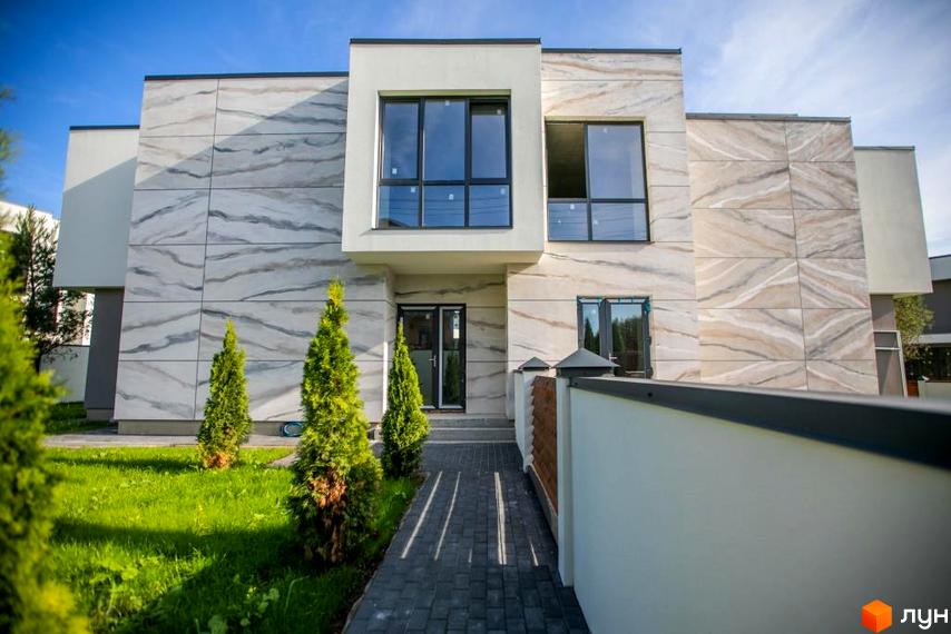 Котеджне містечко КМ Riviera Gold. Фасад будинку оздоблений мармуровими панелями, перед будинком акуратний газон та доріжка з плитки.