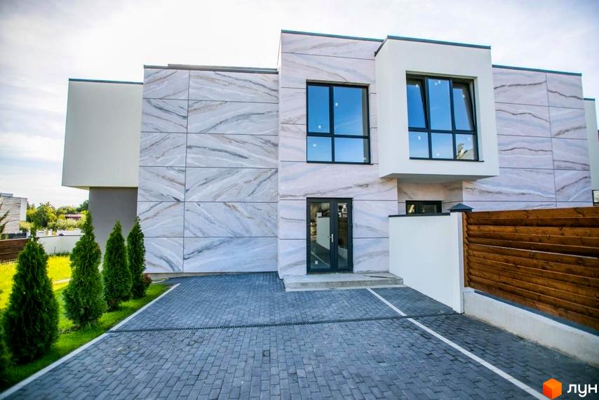 Зовнішній вигляд будинку житлового комплексу КМ Riviera Gold з мармуровим фасадом та великими вікнами. Прибудинкова територія з бруківкою та зеленими насадженнями.