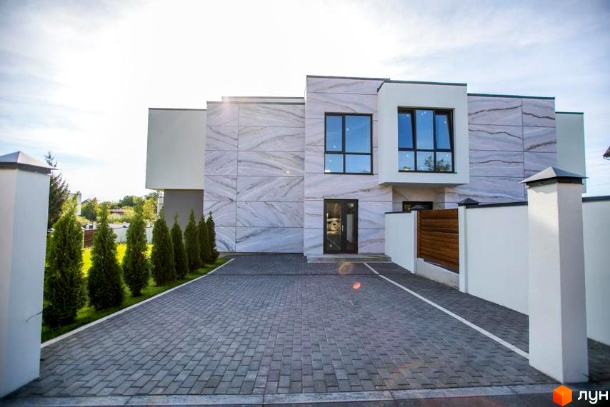 Котеджне містечко КМ Riviera Gold. Зовнішній вигляд будинку з мармуровим фасадом, панорамними вікнами та брукованою прибудинковою територією.