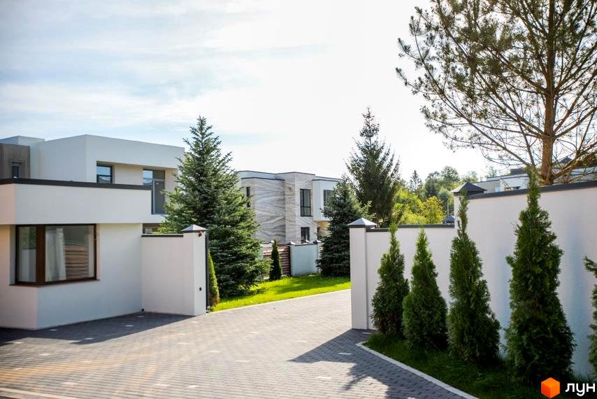 Котеджне містечко КМ Riviera Gold: білі двоповерхові будинки з великими вікнами, доглянута прибудинкова територія з газоном та туями.