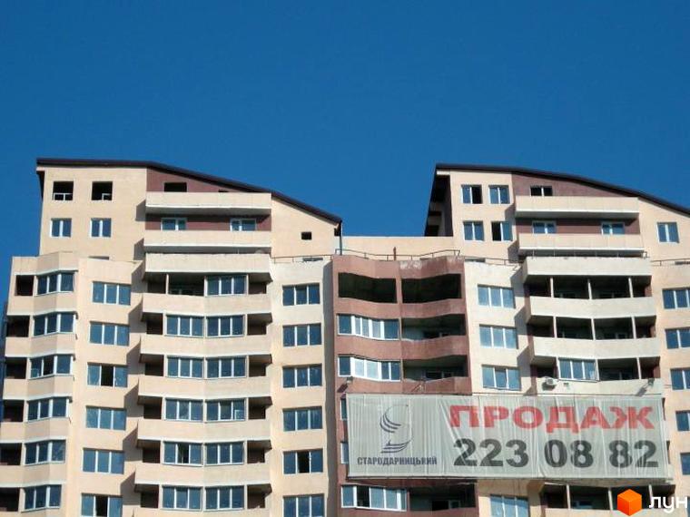 Житловий комплекс Стародарницький з багатоповерховими будинками та балконами. Прибудинкова територія без зелених насаджень.