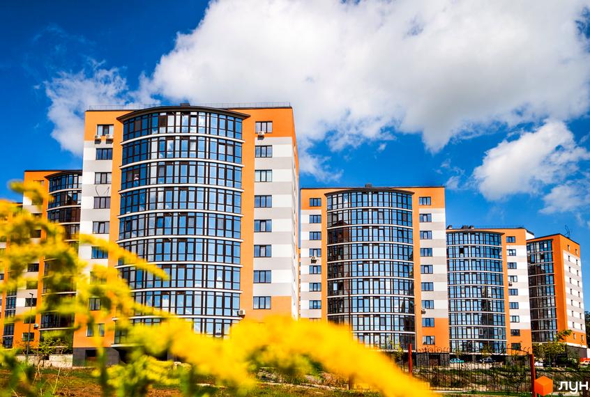 Зображення фасаду та скляних балконів Житлового комплексу Містечко Соборне. Вигляд новобудови з прибудинковою територією та зеленню.