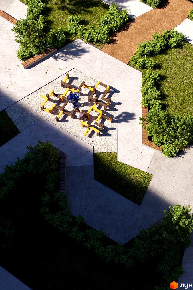 Житловий комплекс Avalon Yard: дитячий майданчик з дерев'яними елементами та синіми кулями на піщаному покритті. Навколо зелені насадження та бруківка.