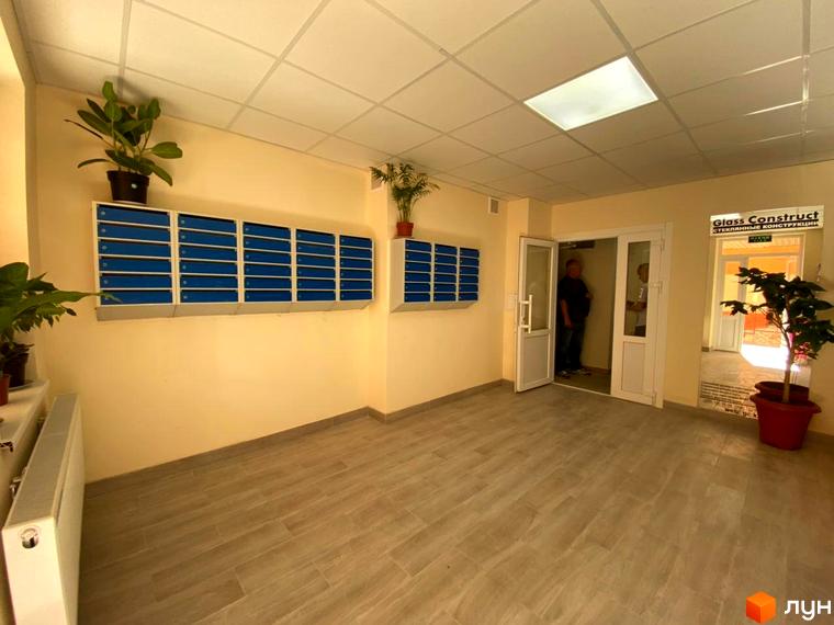 Під'їзд житлового комплексу Металіст з поштовими скриньками та дверима до ліфтового холу. Оздоблення стін та підлоги виконано в спокійних тонах.