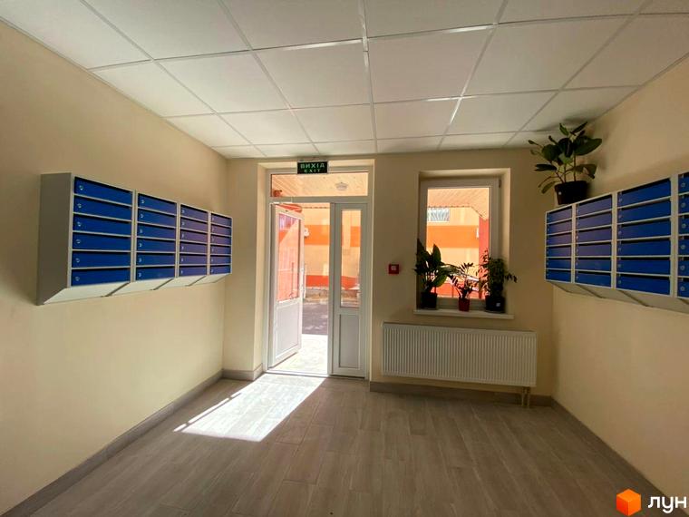 Вхідна група житлового комплексу Металіст з поштовими скриньками та вікном з рослинами. Внутрішній простір новобудови.