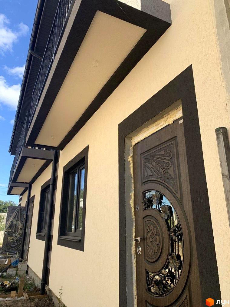 Таунхауси Smart House з темними віконними рамами та дверима на світлому фасаді. Зовнішній вигляд будинку з балконом та елементами декору.