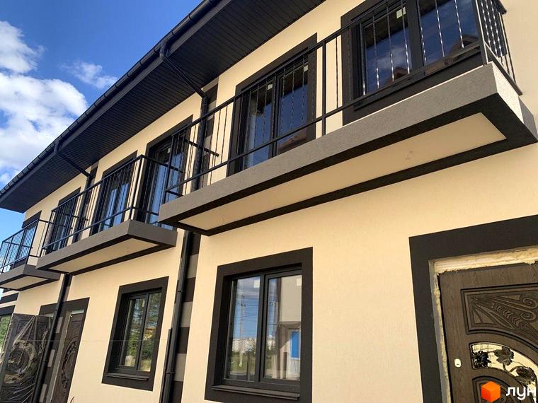 Зовнішній вигляд таунхаусів Smart House з балконами та вікнами з чорними рамами. Фасад будинку світло-бежевого кольору з темними декоративними елементами.