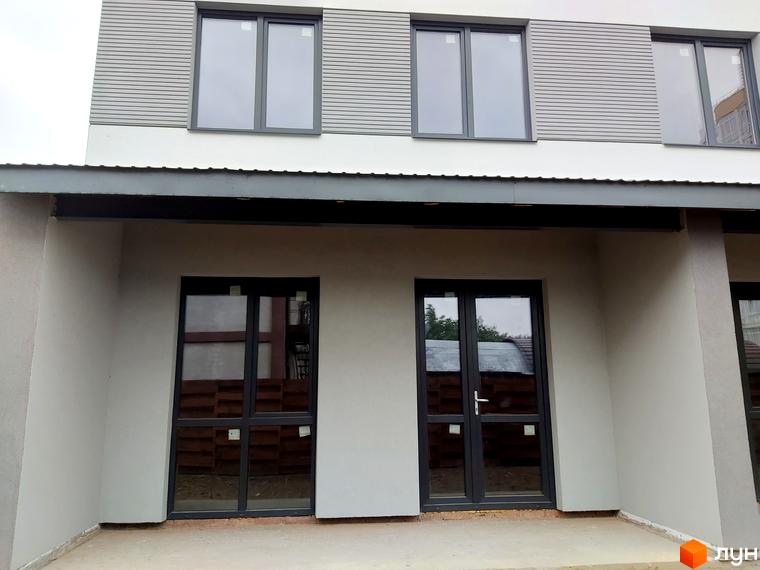 Зовнішній вигляд новобудови на вул. Сергія Колоса, 169. Фасад оздоблений горизонтальними панелями та великими вікнами. Перед будинком розташовані двері з склінням.