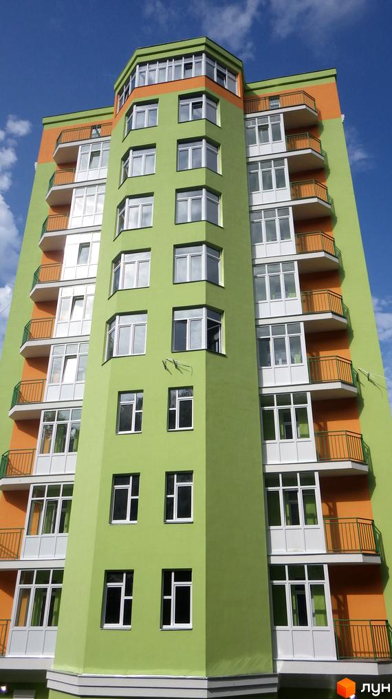 Житловий комплекс вул. Кирилівська, 85/87а з яскравим фасадом та балконами. Прибудинкова територія з зеленими насадженнями.