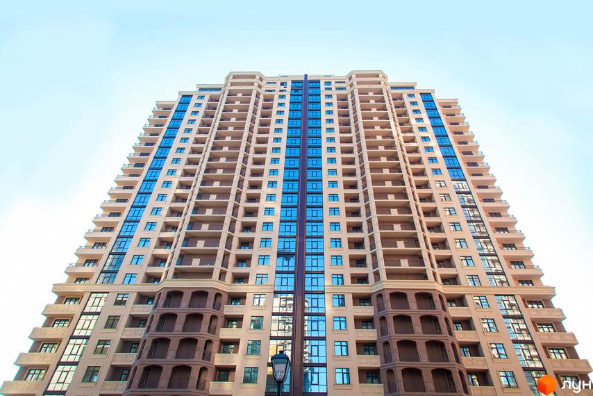 Елегія Парк - це новий житловий комплекс з високою будівлею та численними балконами. Фасад будинку оздоблений світлим оздобленням та синіми вікнами.