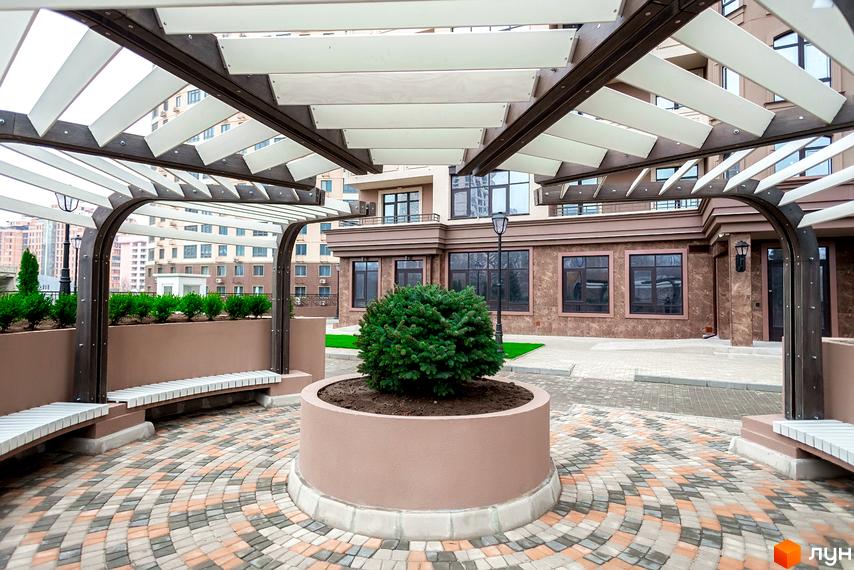 Житловий комплекс Елегія Парк. Зовнішній вигляд будинку та облаштована прибудинкова територія з перголою, лавками та зеленими насадженнями.