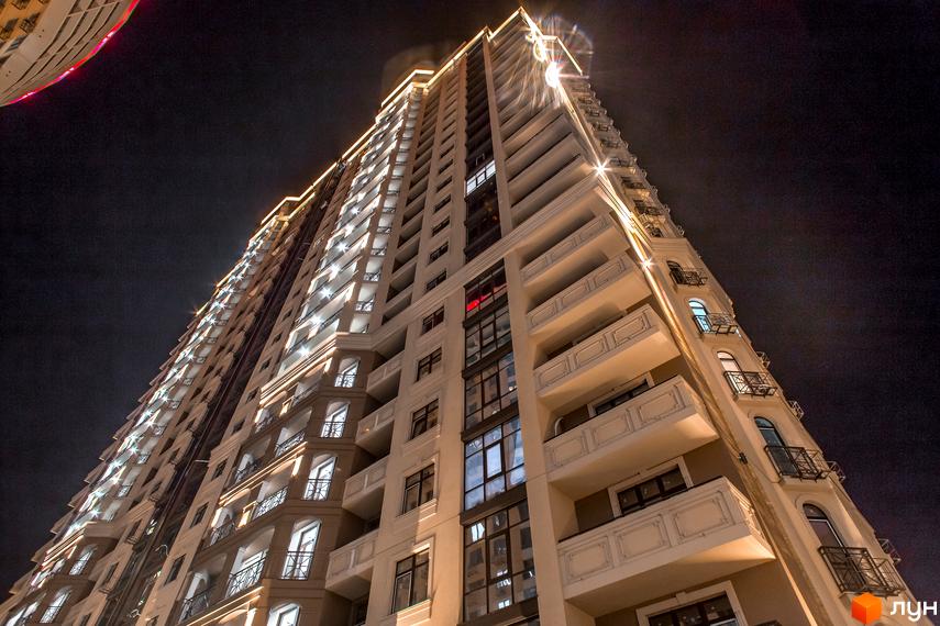 Житловий комплекс Елегія Парк вночі. Висотна будівля з балконами та вікнами, освітлена зовнішнім підсвічуванням.