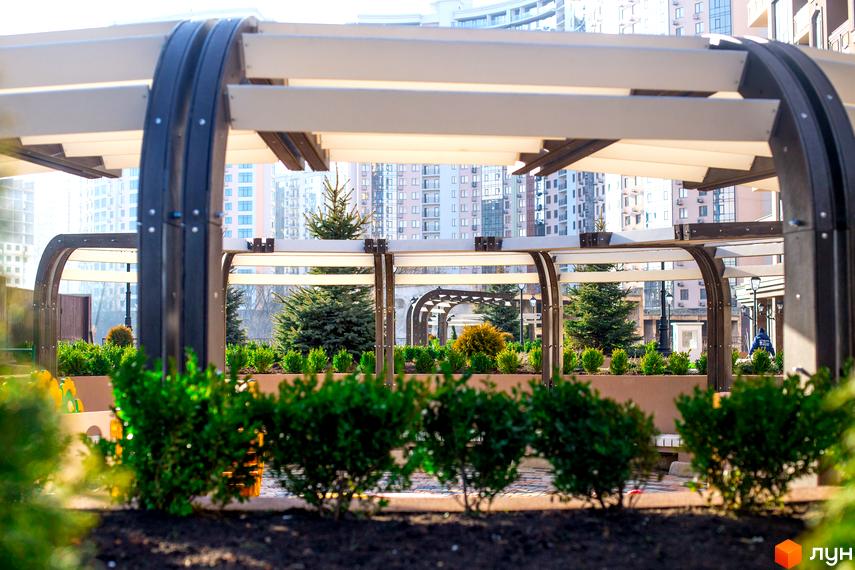 Житловий комплекс Елегія Парк. Сучасна архітектура та зелена прибудинкова територія з деревами та кущами.