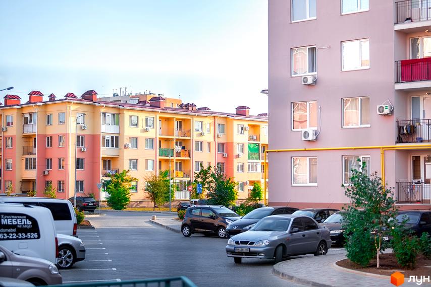 Зовнішній вигляд житлового комплексу ЖМ Сьоме Небо з парковкою та зеленими насадженнями на прибудинковій території.