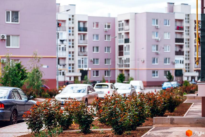 Житловий комплекс Сьоме Небо з сучасними багатоповерхівками та озелененою прибудинковою територією, автомобілі на парковці.