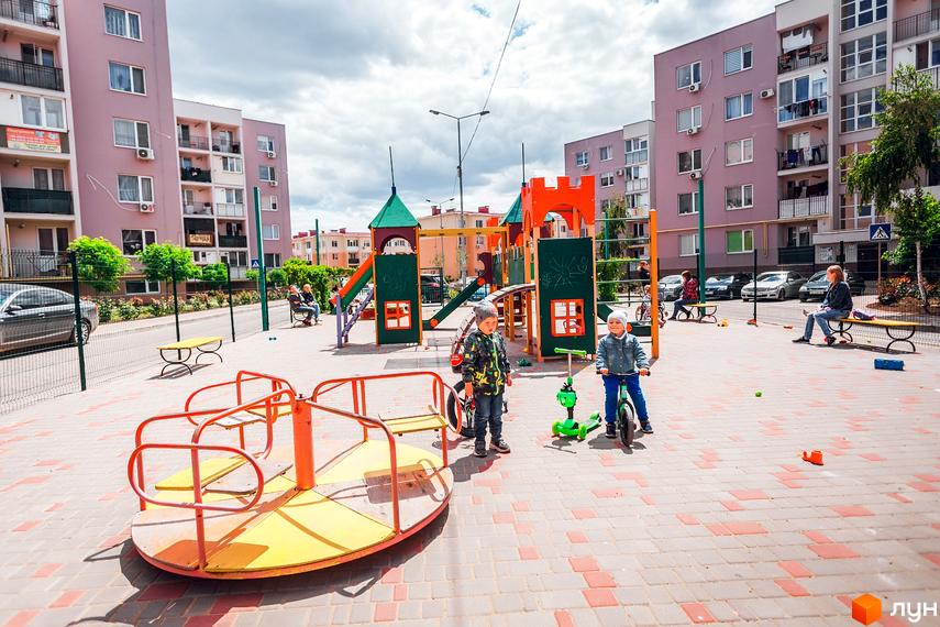 Житловий комплекс Сьоме Небо з сучасними будинками та дитячим майданчиком на прибудинковій території.