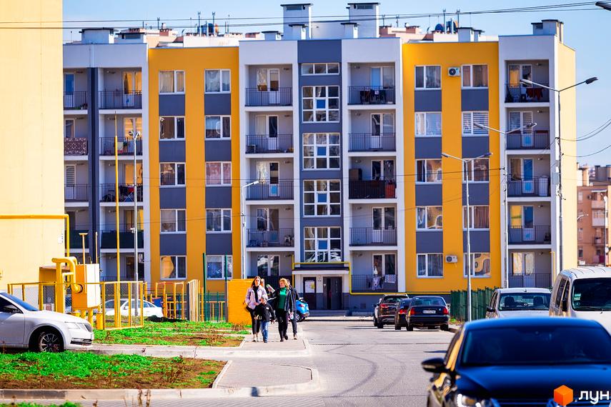 Житловий комплекс Сьоме Небо з яскравими фасадами. Прибудинкова територія з зеленими насадженнями і автомобілями.