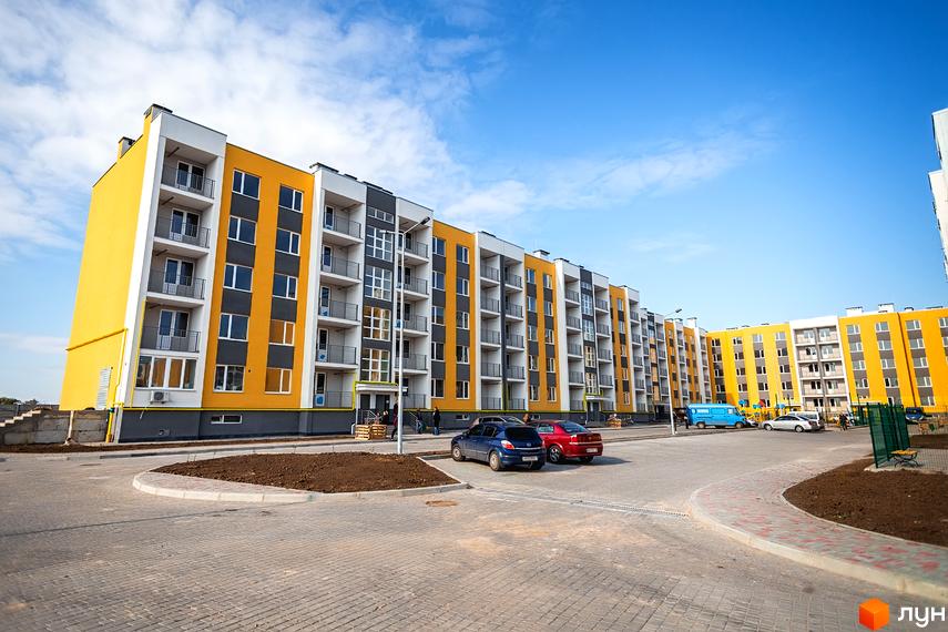 Житловий комплекс ЖМ Сьоме Небо з жовтими та сірими фасадами. Прибудинкова територія з парковкою та зеленими насадженнями.