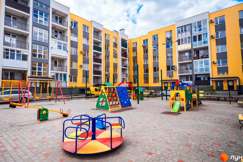 Житловий комплекс ЖМ Сьоме Небо з яскравими фасадами та прибудинковою територією з дитячим майданчиком.