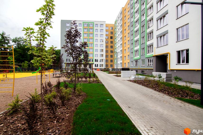 Житловий комплекс 3V Volkova. Зовнішній вигляд будівель з різнокольоровими фасадами та облаштована прибудинкова територія з дитячим майданчиком та доріжками.