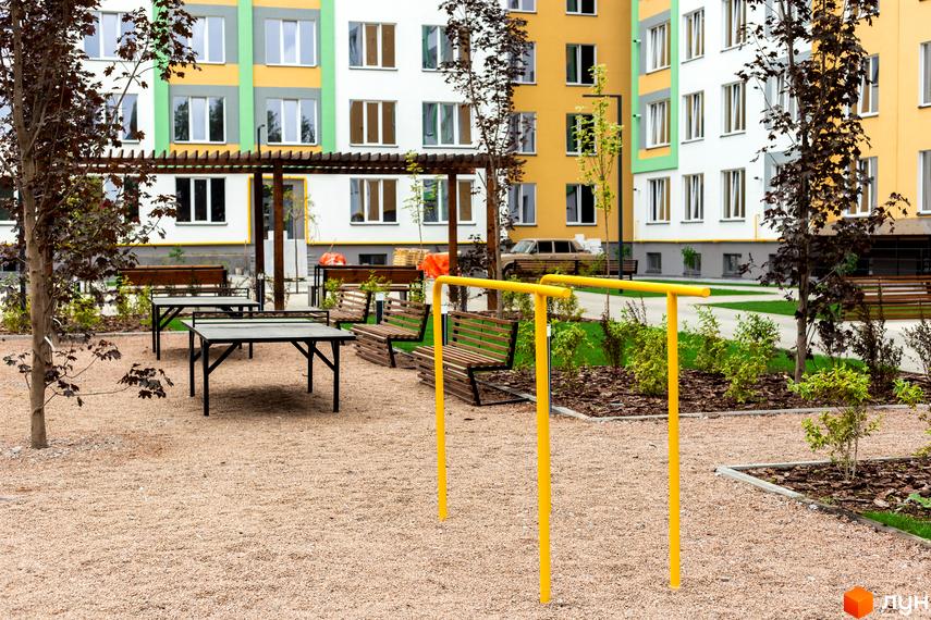 Житловий комплекс 3V Volkova: різнокольорові фасади будівель, зони відпочинку з лавками та столами, спортивні снаряди на прибудинковій території.