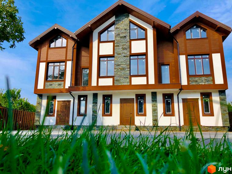Зовнішній вигляд таунхаусів «Київ Шале» з фасадом з дерева та каменю. На передньому плані зелений газон.