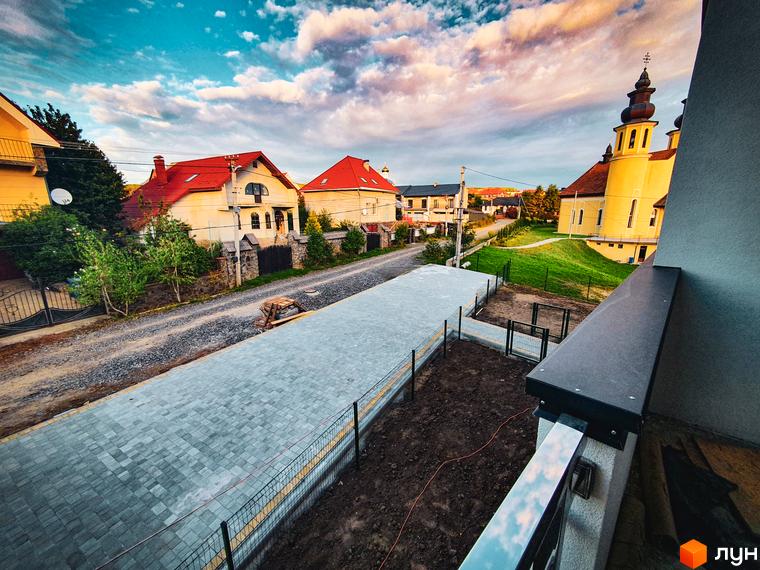 Житловий комплекс Клубний: затишні будинки з червоними дахами та доглянута прибудинкова територія з брукованими доріжками. Чудовий вид на церкву та околиці.