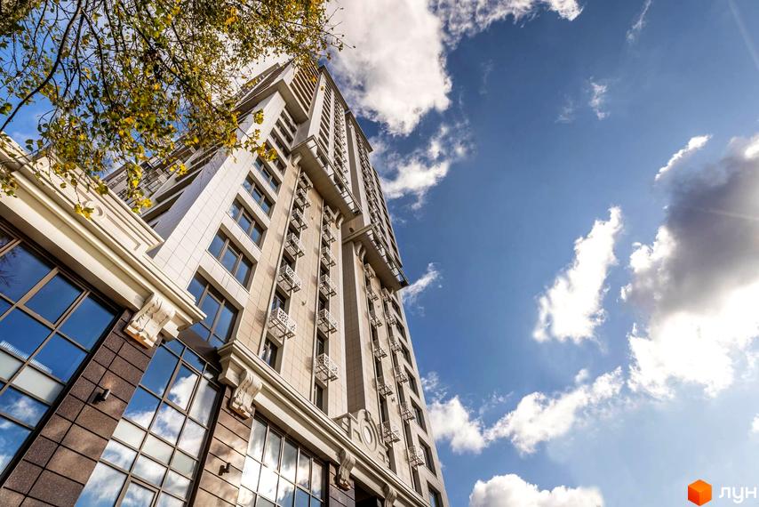 Житловий комплекс Тридцять восьма перлина з сучасним фасадом та великими вікнами. Прибудинкова територія озеленена деревами та кущами.