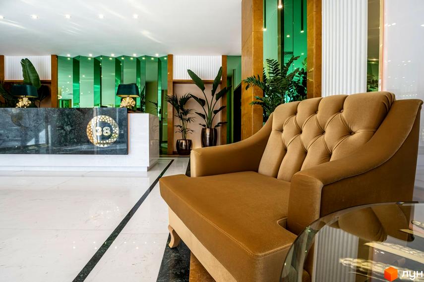 Інтер'єр житлового комплексу Тридцять восьма перлина з рецепцією, диваном та зеленими рослинами.