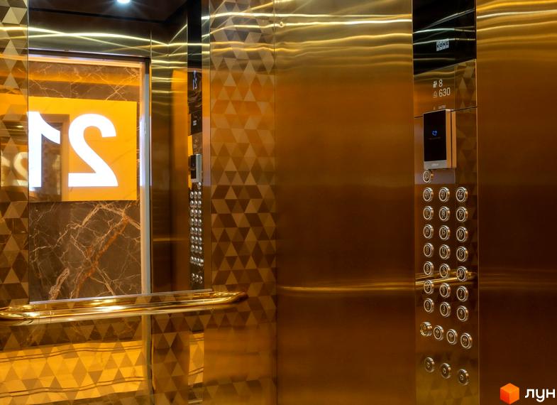 Сучасний ліфт у житловому комплексі Тридцять восьма перлина з золотистими елементами та кнопками управління.