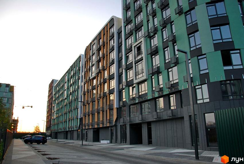 Багатоповерхові будинки Житлового комплексу Respublika з різнокольоровими фасадами та великими вікнами. Перед будинками облаштована дорога та місця для паркування.