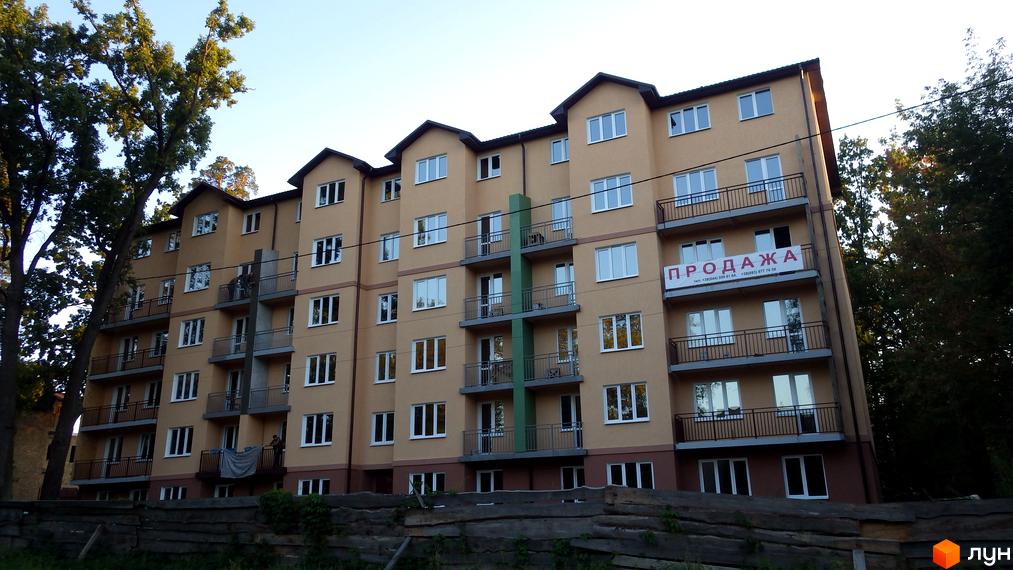Багатоповерховий будинок з балконами та вікнами. На фасаді будівлі розміщено банер з написом «ПРОДАЖА».