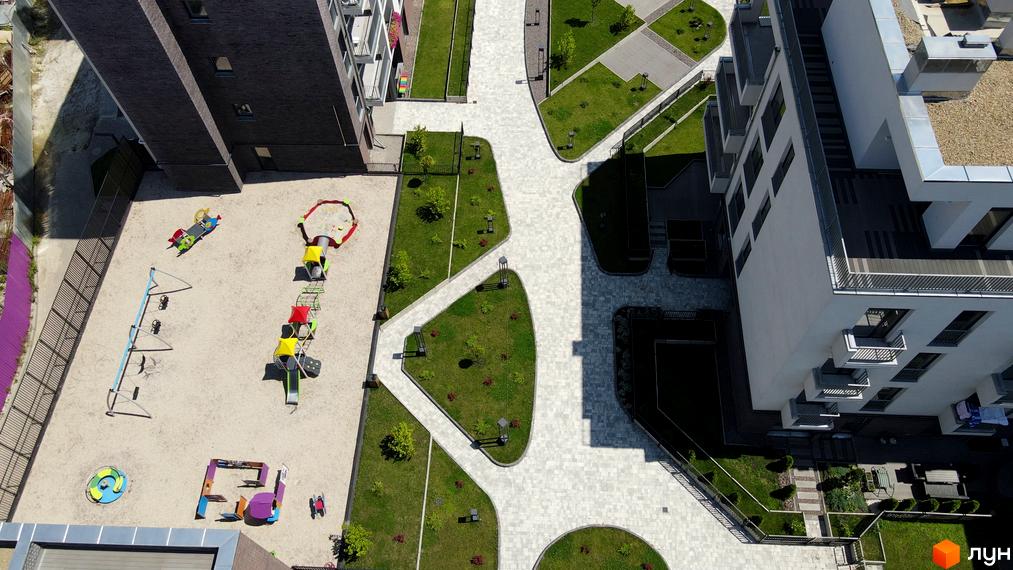 Вигляд згори на житловий комплекс Villa Magnolia з дитячим майданчиком та зеленими зонами. Сучасна архітектура будівель та доглянута прибудинкова територія.
