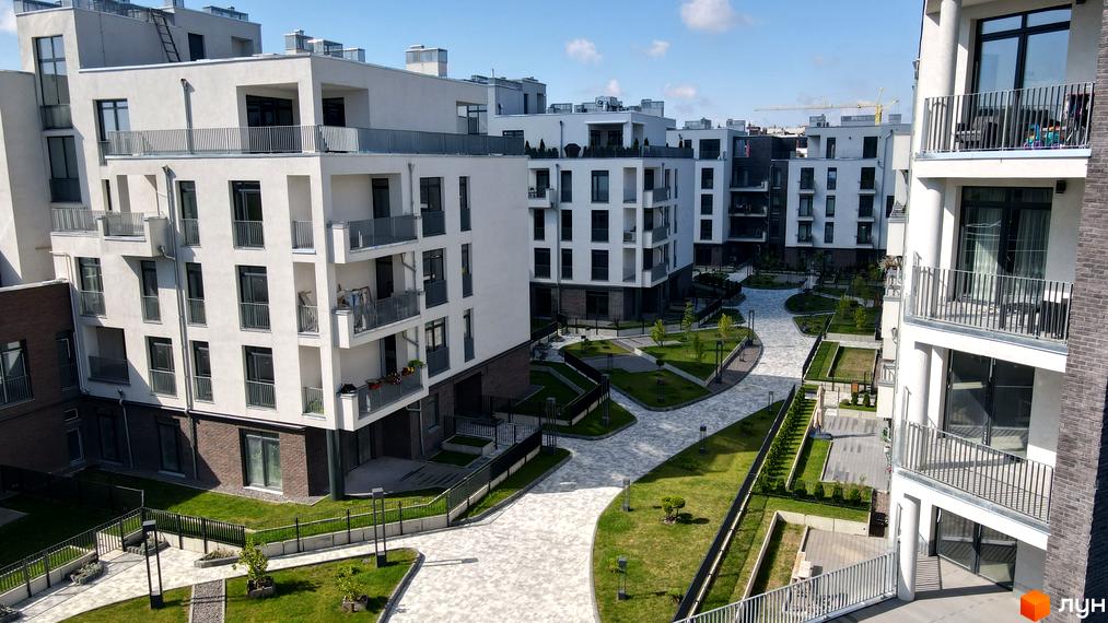 Житловий комплекс Villa Magnolia: білі багатоквартирні будинки з балконами та прибудинкова територія з доріжками та зеленими насадженнями.