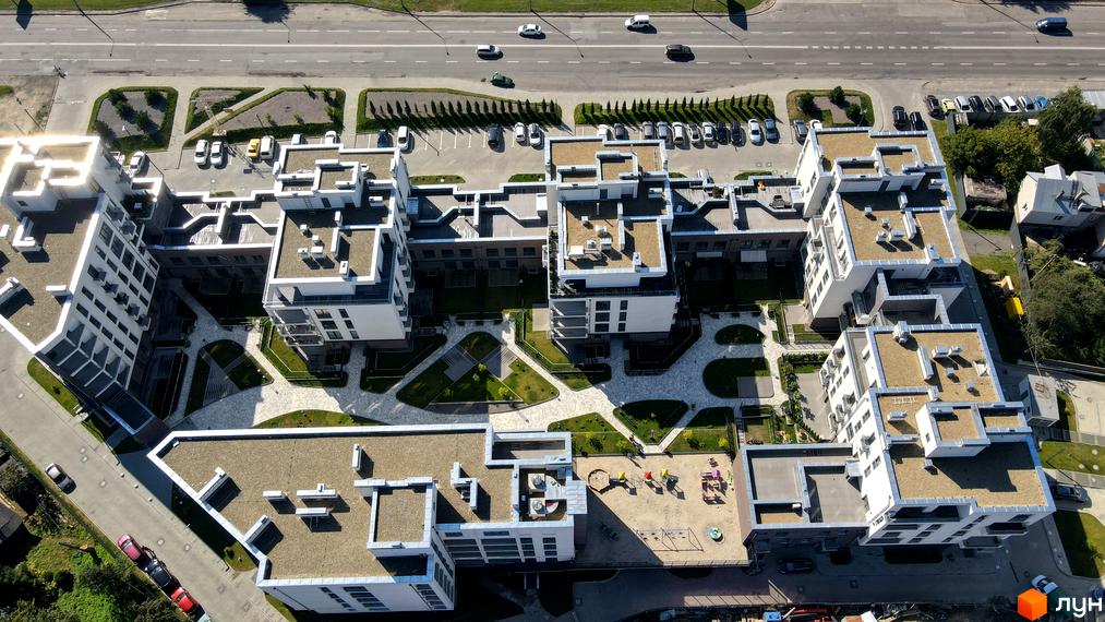 Вид згори на житловий комплекс Villa Magnolia з білими фасадами та пласкими дахами. На прибудинковій території облаштований дитячий майданчик та зелені зони.