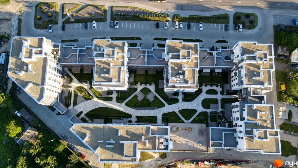 Вид зверху на житловий комплекс Villa Magnolia з білими фасадами та пласкими дахами. Навколо комплексу розташовані зелені зони та доріжки.