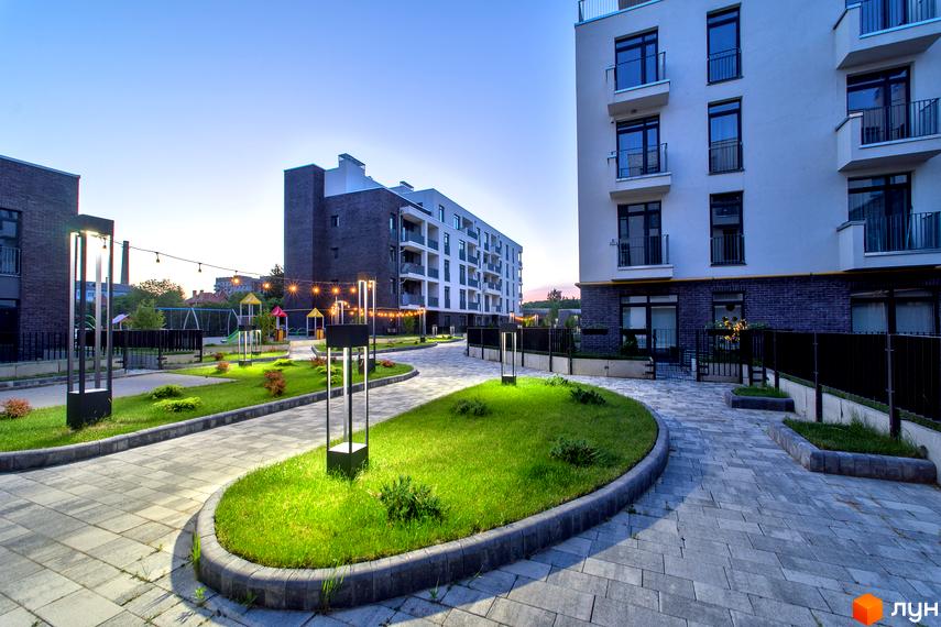 Житловий комплекс Villa Magnolia: фасади будинків з балконами та прибудинкова територія з доріжками, газоном та освітленням.
