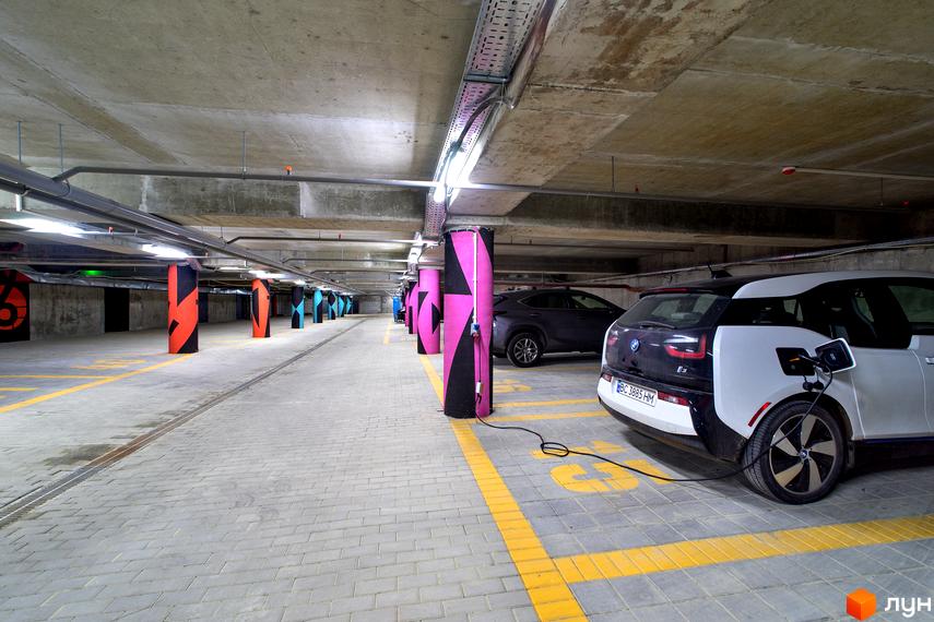 Паркінг в ЖК Villa Magnolia з зарядними станціями для електромобілів. Сучасний паркінг з кольоровими колонами та зручними паркувальними місцями.