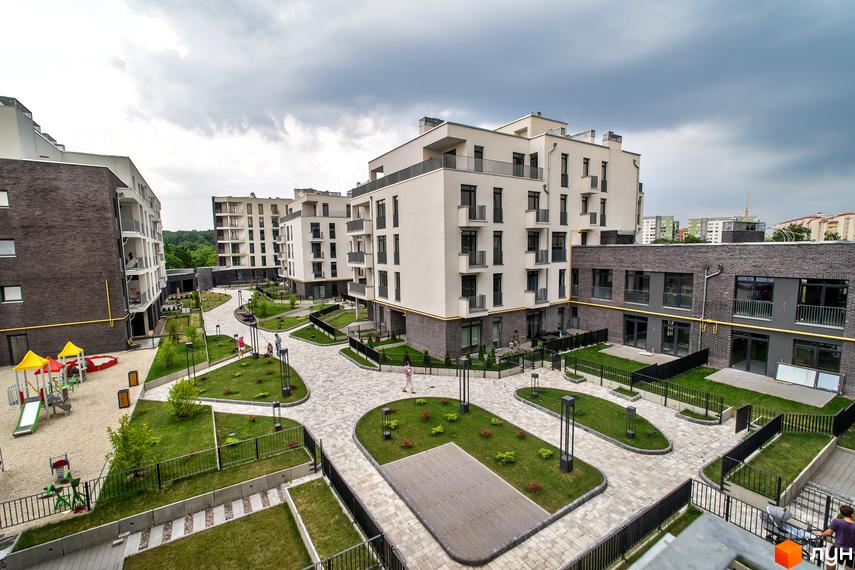 Житловий комплекс Villa Magnolia з білими фасадами та цегляними елементами, облаштованим внутрішнім двором з газонами та дитячим майданчиком.