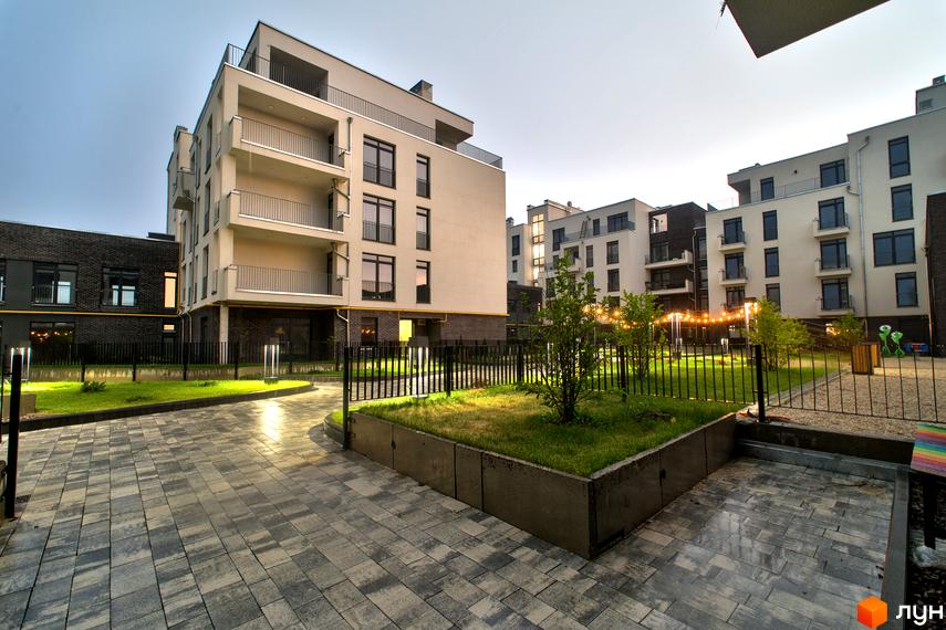 Житловий комплекс Villa Magnolia. Зовнішній вигляд будівель та прибудинкова територія з бруківкою та зеленими насадженнями.