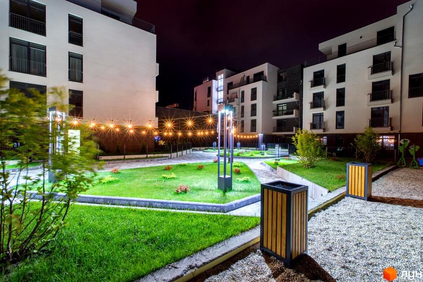 Житловий комплекс Villa Magnolia: багатоповерхові будівлі з балконами вночі. Прибудинкова територія з газоном, освітленням та доріжками.