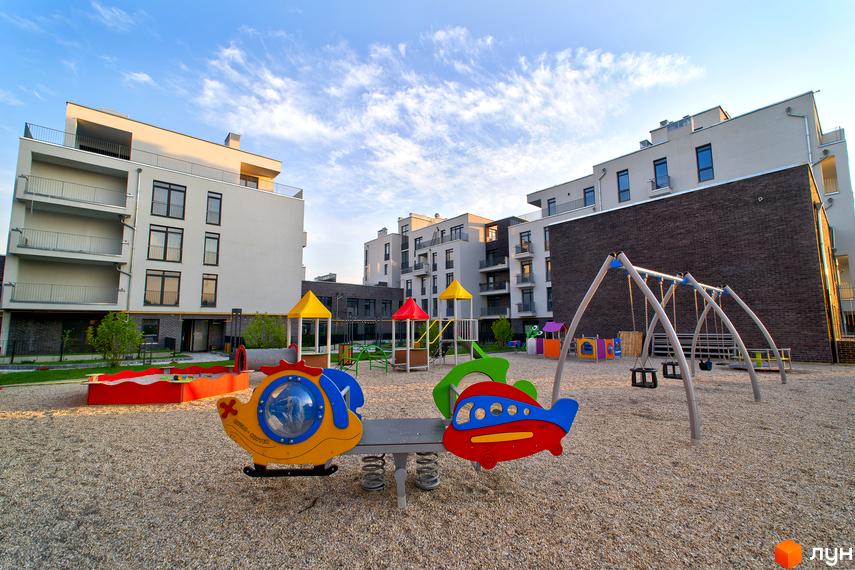 Житловий комплекс Villa Magnolia: сучасні будинки з балконами та дитячий майданчик з гойдалками та ігровими елементами.