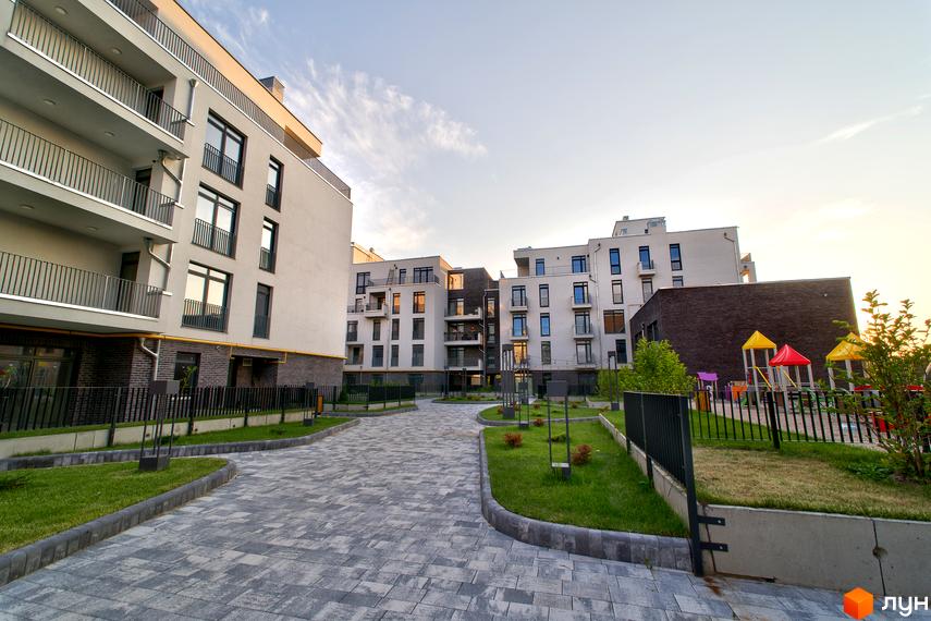 Житловий комплекс Villa Magnolia. Зовнішній вигляд будівель та прибудинкова територія з дитячим майданчиком.