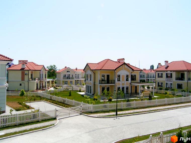 Зовнішній вигляд котеджного комплексу КМ Аріадна з зеленими прибудинковими територіями та доріжками.