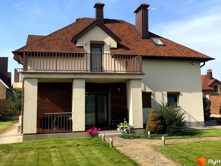 Котеджне містечко Барвіта: двоповерховий будинок з коричневим черепичним дахом, балконом та доглянутою зеленою прибудинковою територією.