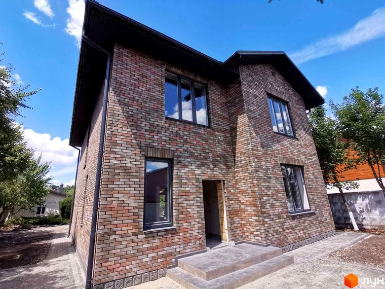 Котеджне містечко КМ English village: двоповерховий будинок з цегляним фасадом та сірими вікнами. Навколо будинку облаштована прибудинкова територія з доріжками та деревами.