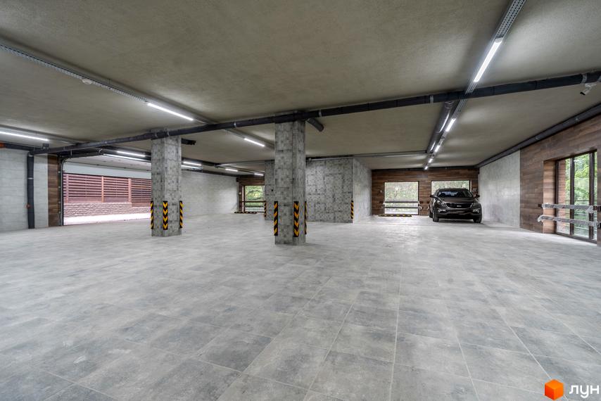 Паркінг у житловому комплексі на вул. Ломаківська (Мічуріна), 19б. Підземний паркінг з бетонною підлогою та колонами, освітленням та вікнами назовні.