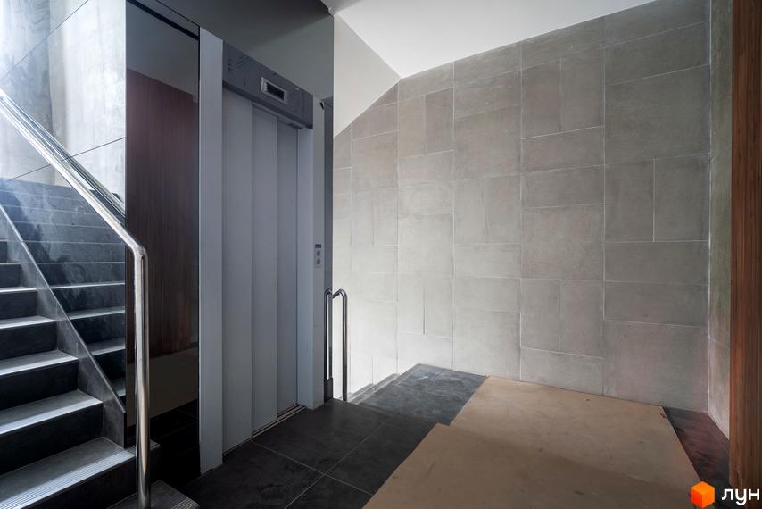 Зовнішній вигляд новобудови на вул. Ломаківська (Мічуріна), 19б, з ліфтом та сходами. Внутрішній простір з плиткою на стінах та підлозі.